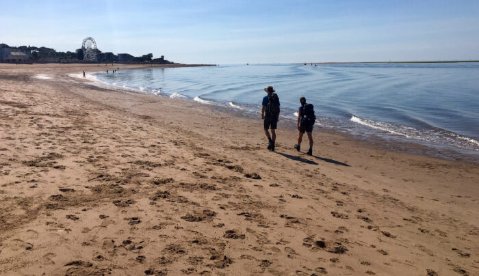 Hikers walking on the beach on the South West Coast Path