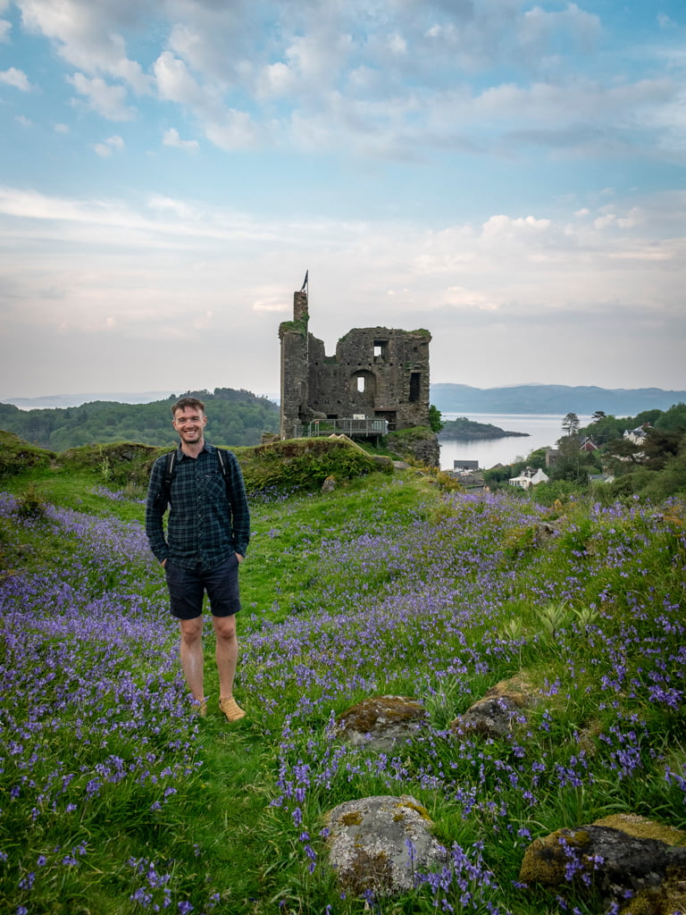 Man standing outside Tarbert Castle with bluebells
